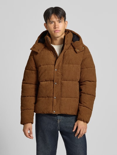 Männermodel trägt Steppjacke in Cord-Optik von Superdry, braune Farbe, gerade Passform, Kapuze, Ganzkörperansicht von vorne. Herrenmodell, Rückenlänge 72 cm, Schulterbreite 48 cm, Brustweite 60 cm, Ärmellänge 70 cm.