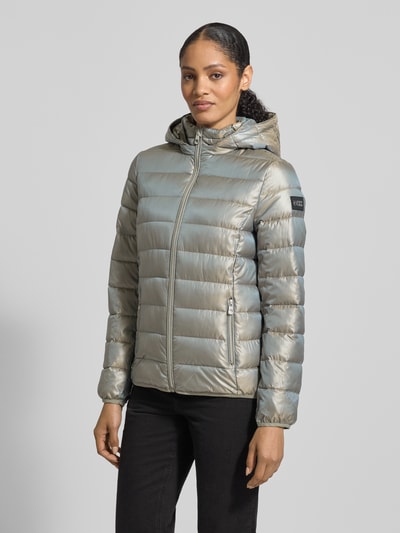 Modelka nosi Jacke mit Kapuze od NAUTGÅRD w kolorze srebrnym, pikowana tekstura, kaptur, ukryty zamek, detal z logo, widok z przodu, całe ciało. Długość pleców w rozmiarze M: 90 cm, szerokość ramion w rozmiarze M: 45 cm, szerokość w biuście w rozmiarze M: 56 cm, długość rękawa w rozmiarze M: 60 cm, luźny krój, troczek, pasek na rękawie.