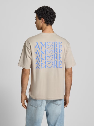 Männermodel trägt Regular Fit T-Shirt aus reiner Baumwolle Modell 'CASPIAN AIRFLEX AMORE' von Only & Sons in Beige mit blauem Print, unifarben, kühlend, atmungsaktiv, Ganzkörperansicht Rückansicht.