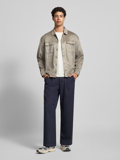 Männermodel trägt Relaxed Fit Hemdjacke mit Brusttaschen und Label-Stitching von Pegador aus beigem Velours, Kentkragen, Knopfleiste, Ganzkörperansicht von vorne. Rückenlänge bei Größe M: 70 cm.