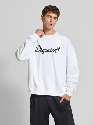 Męski model nosi Relaxed Fit Sweatshirt aus reiner Baumwolle von Dsquared2, białe z czarnym detalem z logo, krój relaxed fit, stójka, elastyczne wykończenia, długość tyłu w rozmiarze M: 67 cm, Ganzkörperansicht von vorne.