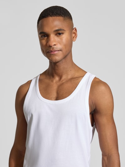 Männermodel trägt weißes Tank Top mit Label-Detail aus Baumwoll-Elasthan-Mix von BOSS, eng anliegend, Nahaufnahme Oberkörper.