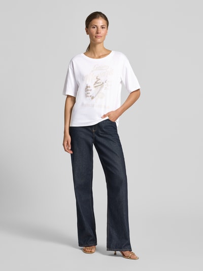 Vrouwenmodel draagt Regular fit dames t-shirt van puur katoen, Model 'Ice Cream' van monari, met siersteentjes, ronde hals, ruglengte bij maat 36: 57 cm, wit met print, recht model, Ganzkörperansicht von vorne.