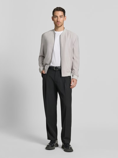 Männermodel trägt Blouson mit seitlichen Eingrifftaschen von MCNEAL, Material-Mix mit Stretch-Anteil, Regular-Fit, Stehkragen, Reißverschluss, elastische Abschlüsse, hellgrau, schwarz-weiße Kontraste, glatte Textur, Ganzkörperansicht von vorne.