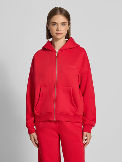 Frauenmodel trägt Relaxed Fit Basic Sweatjacke mit Kapuze von REVIEW in Rot, Baumwoll-Mix, Logo-Print, getrennte Kängurutasche, Ganzkörperansicht von vorne.