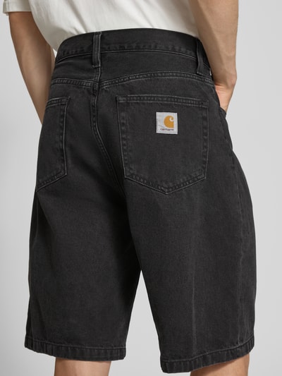 Männermodel trägt Jeansshorts mit Eingrifftaschen Modell 'Robertson' von Carhartt Work In Progress, Reine Baumwolle, Regular-Fit, Ganzkörperansicht Rückansicht.