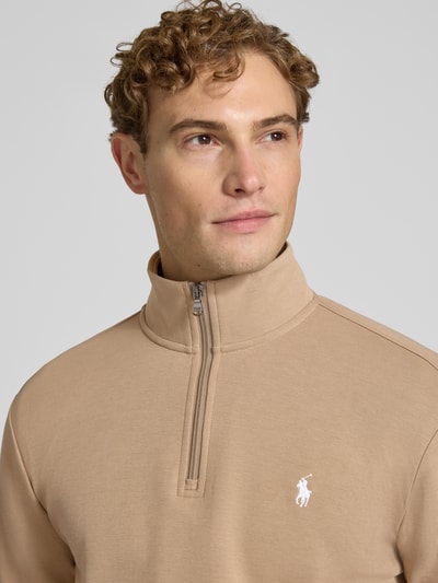 Męski model nosi Regular Fit Troyer aus Baumwoll-Mix von Polo Ralph Lauren w kolorze beżowym, tekstura gładka, zamek z przodu, nahaufnahme górnej części ciała.