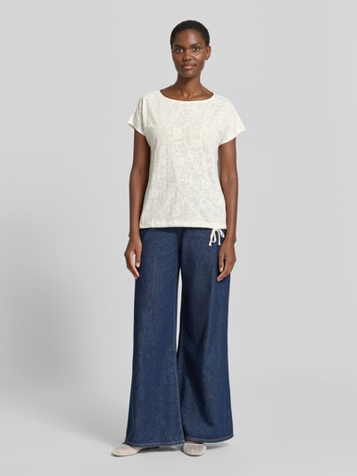 Frauenmodel trägt T-Shirt mit Kordelzug am Saum und Rundhalsausschnitt von Betty Barclay in Offwhite, ganzkörperansicht von vorne. Material-Mix mit Baumwoll-Anteil, Straight Fit, Rückenlänge 60 cm bei Größe 36, lockere Passform, feine florale Textur.