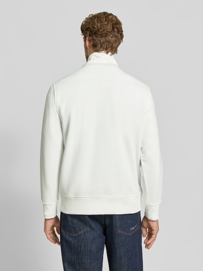 Männermodel trägt weißen Regular Fit Troyer aus Baumwoll-Mix von GANT, glatte Textur, dunkle Jeans, Ganzkörperansicht Rückansicht.