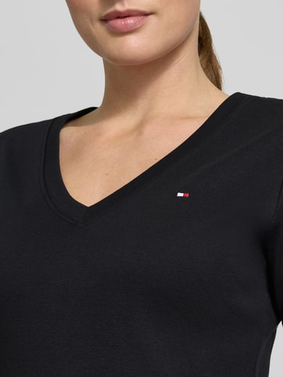 Frauenmodel trägt Slim Fit T-Shirt aus reiner Baumwolle von Tommy Hilfiger, Optik: Unifarben, Logo-Stitching, V-Ausschnitt, Jersey, Nahaufnahme Oberkörper.