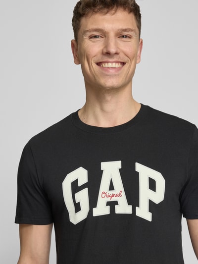 Männermodel trägt schwarzes Herren T-Shirt mit Logo und Rundhalsausschnitt von GAP aus reiner Baumwolle, Regular-Fit, Nahaufnahme Oberkörper.