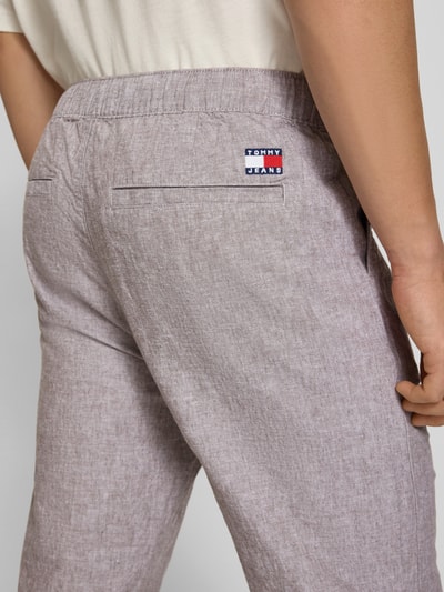 Männermodel trägt Regular Fit Weite Hose aus Leinen-Baumwoll-Mix von Tommy Jeans in Melange-Optik, Materialverarbeitung Flammgarn, Detailaufnahme Rückansicht.