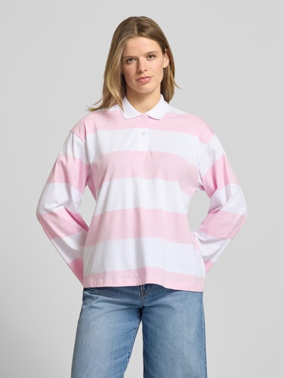 Frauenmodel trägt Relaxed Fit Poloshirt aus reiner Baumwolle Modell 'VILMA' von JJXX in Rosa und Weiß, Langarm, Ganzkörperansicht von vorne.