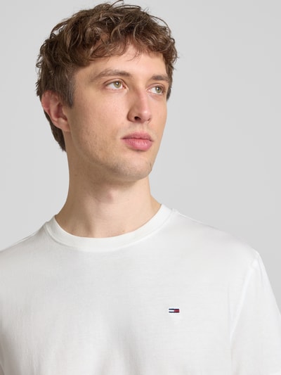 Männermodel trägt Regular Fit T-Shirt aus reiner Baumwolle von Tommy Jeans, unifarben, Logo-Stitching, Nahaufnahme Oberkörper.