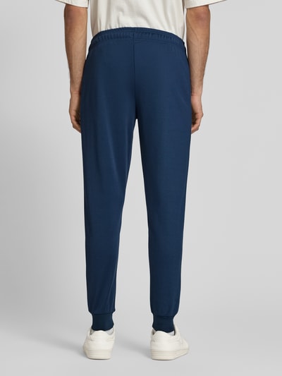 Männermodel trägt Sweatpants mit elastischem Bund Modell 'BERTONI' von Ellesse aus Baumwoll-Mix, Regular-Fit, Label-Detail, Ganzkörperansicht Rückansicht.