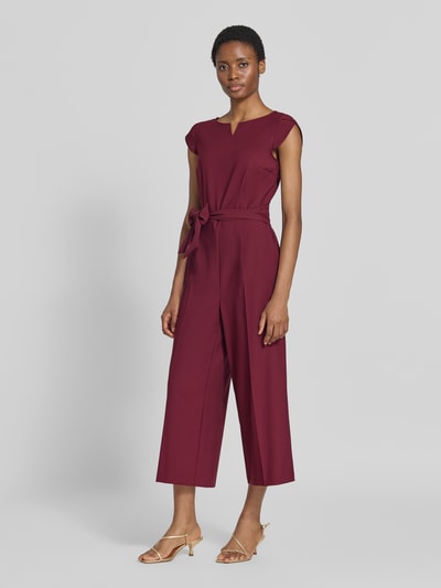 Frauenmodel trägt Regular Fit Jumpsuit mit Bindegürtel von Betty Barclay in Weinrot, glatte Struktur, Ganzkörperansicht von vorne, Damen Jumpsuit von Betty Barclay.