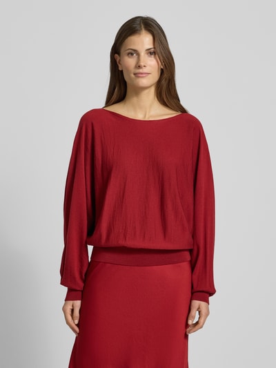 Vrouwenmodel draagt Oversized Strickpullover met U-boothals, model 'GERLINA' van Drykorn, pure scheerwol, rood, geribbelde boorden, volledige voorkantaanzicht.