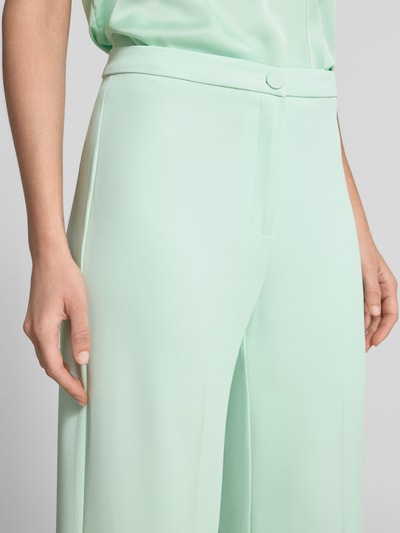 Frauenmodel trägt Stoffhose mit Bügelfalte von Rinascimento in Mintgrün, weiter Schnitt, Material-Mix, Nahaufnahme Oberkörper.