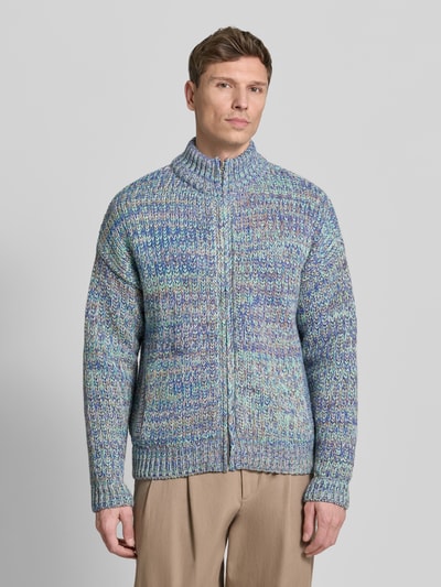 Männermodel trägt Relaxed Fit Strickjacke aus Baumwoll-Woll-Mix mit Viskose-Anteil Modell 'UN-WASTED' von Armedangels, mehrfarbig, Strickoptik, Reißverschluss, Stehkragen, Logo-Detail, seitliche Eingrifftaschen, Ganzkörperansicht von vorne.