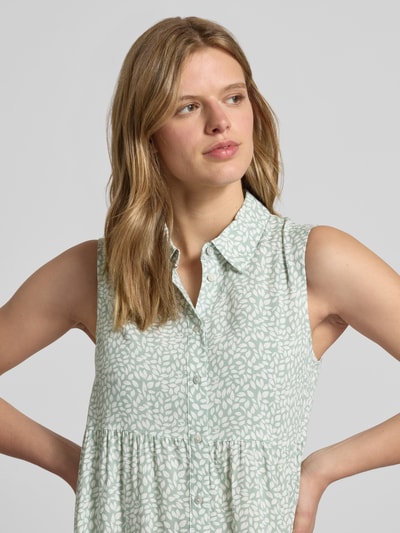 Kobiece modelka nosi sukienkę koszulową z wiskozy Ausgestelltes Hemdblusenkleid aus reiner Viskose Modell 'THEA' od Only, efekt: wzór na całej powierzchni, krój: rozkloszowana, długość mini, kołnierz: kołnierzyk koszulowy, dekolt: dekolt w serek, detale: marszczenie, zapięcie: listwa guzikowa, bez rękawów, dół prosty, materiał: czysta wiskoza, jasne kolory, miękka faktura, nahaufnahme górnej części ciała.
