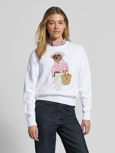 Kobieta modelka nosi Regular Fit Strickpullover aus Baumwoll-Leinen-Mix mit Bear Intarsien od Polo Ralph Lauren, efekt: jednolity kolor, krój: krój regular fit, aplikacja: motyw niedźwiedzia, kształt kołnierza: okrągły dekolt, rękaw: krótki rękaw, zakończenie rękawów: prążkowane, wykończenie materiału: dzianina, materiał: mieszanka bawełny i lnu, kolor biały, faktura gładka, Ganzkörperansicht z przodu.