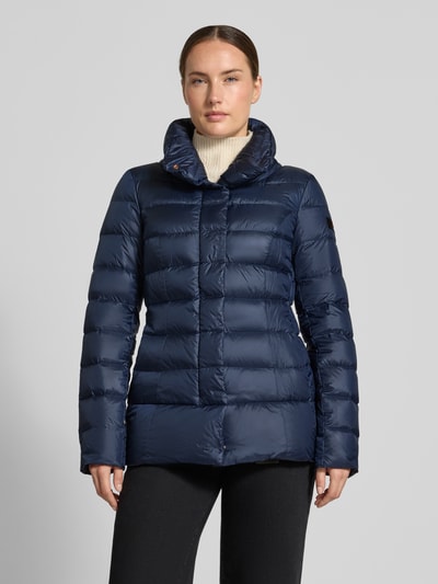 Kobiece model prezentuje kurtkę pikowaną 'Steppjacke mit Eingrifftaschen' od Peuterey w kolorze granatowym, wpuszczane kieszenie, pikowanie, stójka, plisa, długość tyłu w rozmiarze 36: 72 cm, szerokość ramion w rozmiarze 36: 42 cm, szerokość w rozmiarze 36: 44 cm, długość rękawów w rozmiarze 36: 61 cm, pełny widok z przodu.
