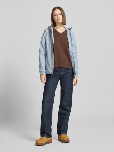 Frauenmodel trägt Funktionsjacke mit DryVent™-Technologie von The North Face in Hellblau, kombiniert mit Jeans, Ganzkörperansicht von vorne.