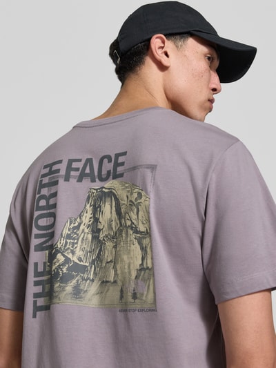 Männermodel trägt T-Shirt mit Logo und Rundhalsausschnitt von The North Face, lila Farbton, Baumwoll-Mix, Rückansicht, Nahaufnahme Oberkörper.