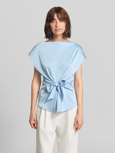 Frauenmodel trägt Blusentop aus Satin mit Schleifen-Detail Modell 'Katarim' von Neo Noir, hellblau, Rundhalsausschnitt, taillierter Schnitt, Ganzkörperansicht von vorne.