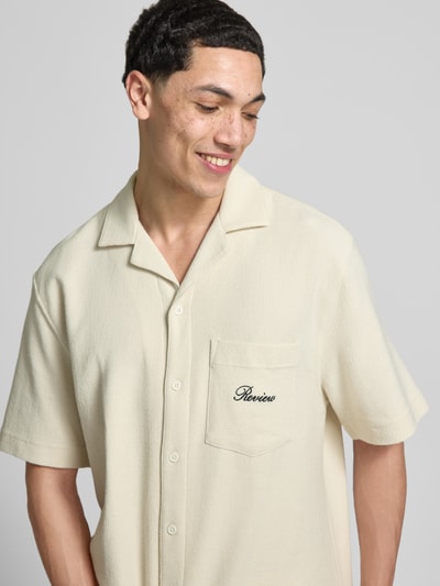 Männermodel trägt Regular Fit Freizeithemd mit Label-Stitching von REVIEW in Creme, Baumwoll-Mix, Reverskragen, Brusttasche, Nahaufnahme Oberkörper.