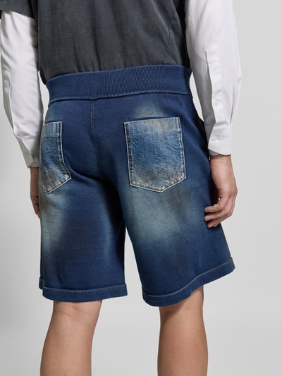 Männermodel trägt Baggy Fit Jeansshorts aus Baumwolle von Dsquared2 in Blau mit Eingriff- und Gesäßtaschen, Label-Detail, Ganzkörperansicht Rückansicht.