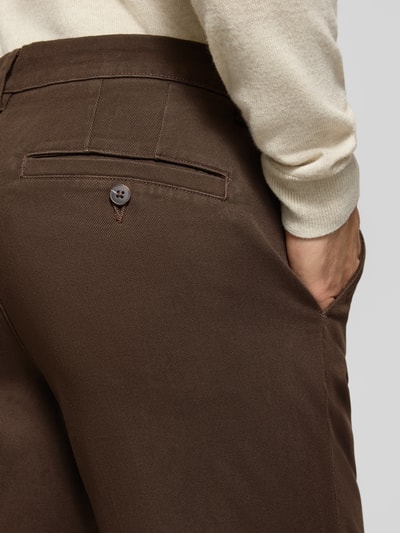 Männermodel trägt Straight Fit Chino aus Baumwoll-Mix Modell 'Miles' von Selected in Dunkelbraun mit glatter Textur, Nahaufnahme Rückansicht, Herren Chino von Selected.