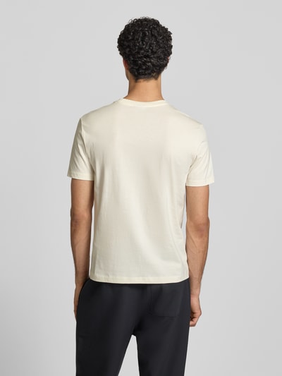 Männermodel trägt T-Shirt mit Label-Stitchings und Rundhalsausschnitt von CHAMPION in Creme, Regular Fit, reine Baumwolle, Rückansicht Ganzkörperansicht.