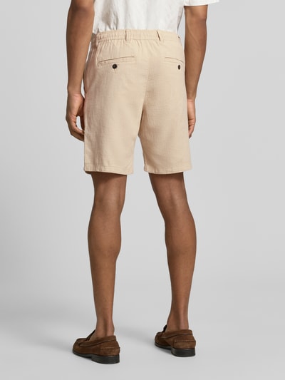 Männermodel trägt Regular Fit Chinoshorts aus Baumwoll-Leinen-Mix Modell 'BRODY' von SELECTED HOMME, unifarben, Textur Flammgarn, Gesäßtaschen mit Knopf, Ganzkörperansicht Rückansicht.