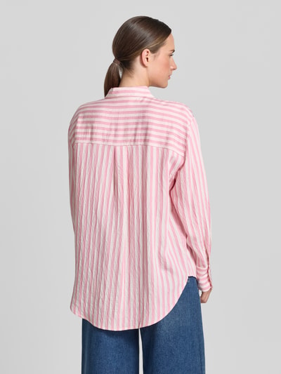 Frauenmodel trägt Relaxed Fit Bluse aus Viskose-Mix von Comma mit rosa-weißen Streifen, Hemdblusenkragen, Knopfleiste, Rückenlänge 76 cm, Ärmellänge 57 cm, Ganzkörperansicht Rückansicht.
