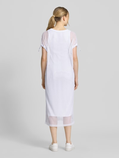 Frauenmodel trägt semitransparentes Midikleid mit Rundhalsausschnitt von Marc Cain in Weiß, Material-Mix mit Stretch-Anteil, gerader Schnitt, Rückansicht Ganzkörperansicht.