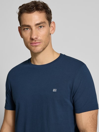Männermodel trägt T-Shirt aus Baumwolle mit Rundhalsausschnitt von Christian Berg Men in Blau mit Label-Detail, Nahaufnahme Oberkörper. Regular-Fit, reine Baumwolle, Rückenlänge bei Größe M 71 cm.