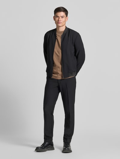 Männermodel trägt Relaxed Fit T-Shirt aus reiner Baumwolle Modell 'ASPEN' von SELECTED HOMME in Braun, schlichter Look, Ganzkörperansicht von vorne.