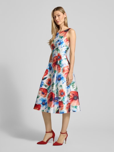 Frauenmodel trägt Knielanges Cocktailkleid im Allover-Look von Vera Mont, A-Linie, bunte Blumen, in Weiß-Rot-Blau, Ganzkörperansicht von vorne.