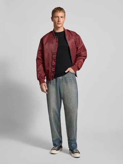 Männermodel draagt Slim Fit Longsleeve met ribstructuur van Tommy Jeans in zwart, puur katoen, geborduurd logo, ronde hals, Ganzkörperansicht von vorne.