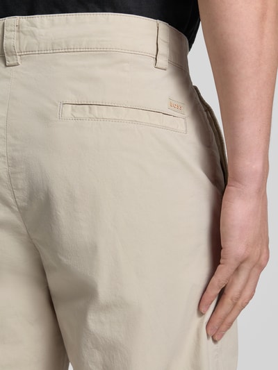 Männermodel trägt Straight Fit Chino aus Baumwoll-Mix von BOSS Orange, Beige mit glatter Oberfläche, Nahaufnahme Rückansicht.