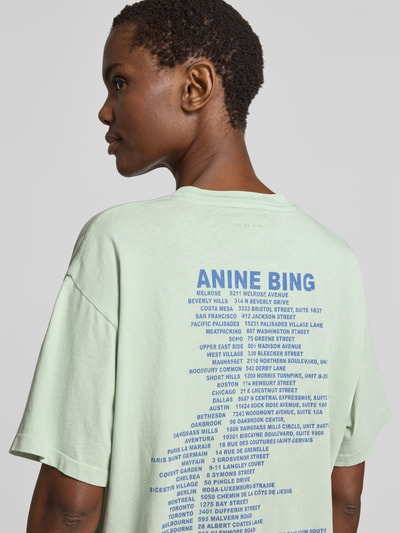 Frauenmodel trägt Oversized T-Shirt mit Logo-Print von Anine Bing aus reiner Baumwolle in Mint mit Rundhalsausschnitt, Rückenlänge 62 cm, Nahaufnahme Oberkörper von hinten.