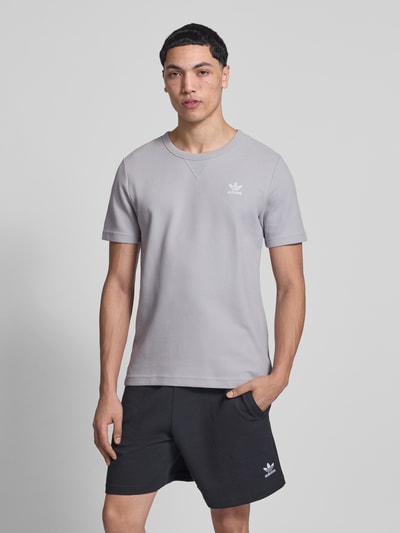 Männermodel trägt Regular Fit T-Shirt mit Baumwoll-Anteil von adidas Originals, Optik: Unifarben, Waffel-Struktur, Logo-Stitching, Rundhals, Kurzarm, Ganzkörperansicht von vorne.