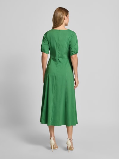 Vrouwenmodel draagt groen Midikleid met Raffungen van More & More uit katoenmix, getailleerd, ronde hals, stolpplooi, halflange mouwen, ruglengte 119 cm, maat 36. Ganzkörperansicht Rückansicht.
