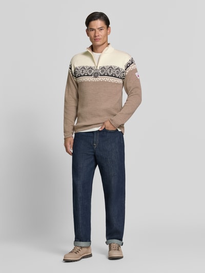 Männermodel trägt Wollpullover mit Troyer-Kragen Modell 'Moritz' von Dale of Norway in Beige und Creme, gerader Schnitt, Ganzkörperansicht von vorne. Reine Wolle, Label-Detail, Rückenlänge bei Größe M: 72 cm, Ärmellänge: 64 cm.