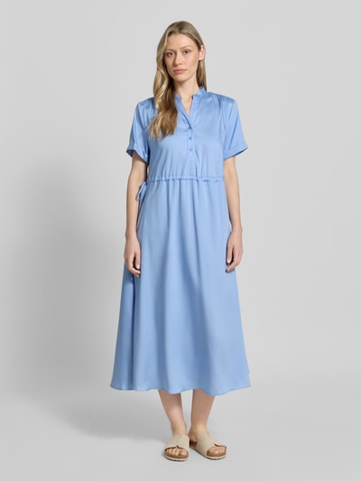Frauenmodel trägt Midikleid aus Lyocell mit V-Ausschnitt von More & More in Hellblau, regulierbares Taillenband, A-Linie, Stehkragen, Knopfleiste, kurze Ärmel mit Aufschlag, Rückenlänge 123 cm, Brustweite 52 cm, Ärmellänge 21 cm, Ganzkörperansicht von vorne.