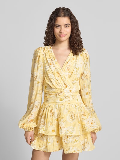 Frauenmodel trägt Minikleid aus Viskose-Mix mit Rüschenbesatz von Gina Tricot, gelb gemustert, tailliert, langärmelig, Nahaufnahme Oberkörper.
