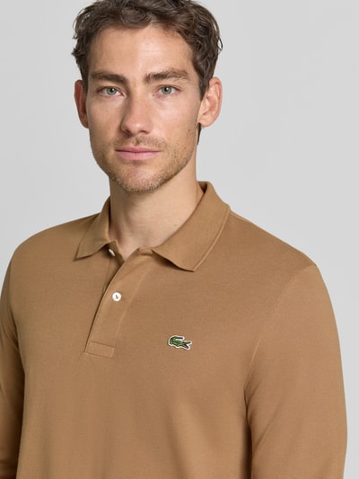 Männermodel trägt Regular Fit Poloshirt aus reiner Baumwolle von Lacoste in Braun mit glatter Textur und Polokragen, Nahaufnahme Oberkörper.