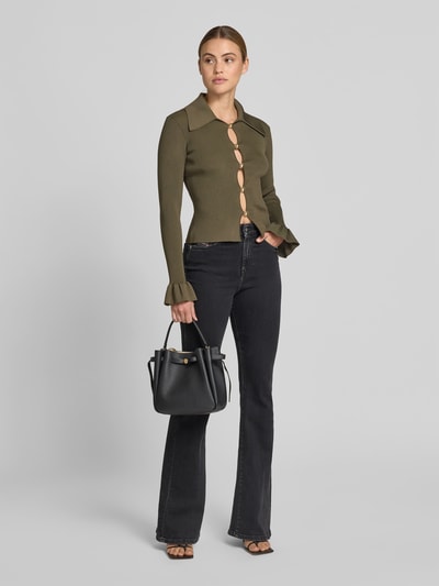 Frauenmodel trägt Bucket-Bag mit Logo-Detail von Tory Burch in Schwarz mit Strukturmuster, Magnetverschluss, Tunnelzug und abnehmbarem Schulterriemen, Hauptfach, Breite 23 cm, Länge 22 cm, Tiefe 10 cm, Ganzkörperansicht von vorne.