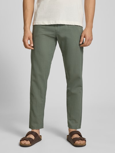 Męski model nosi Hose aus Baumwoll-Leinen-Mix Modell 'KANE' von Jack & Jones w kolorze zielonym, krój regular fit, bawełniano-lniana struktura, elastyczny pas, szerokość w rozmiarze M: 41 cm, długość nogawki od wewnątrz w rozmiarze M: 81 cm, zdjęcie całej sylwetki z przodu.